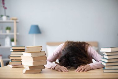 Evde kitaplarla masada yatan bir kadın. Konsept öğrenimi.