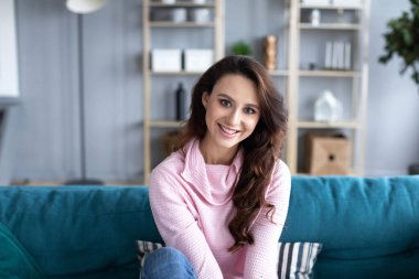 Oturma odasındaki kanepede gülümseyen güzel bir kadın. Evde kalan bir kızın portresi..