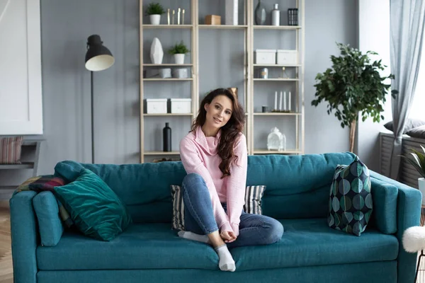 Oturma odasındaki kanepede gülümseyen güzel bir kadın. Evde kalan bir kızın portresi..