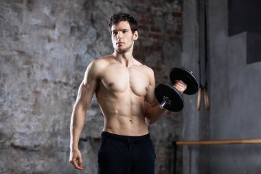 Vücut geliştirici, spor salonunda dambılla egzersiz yap..