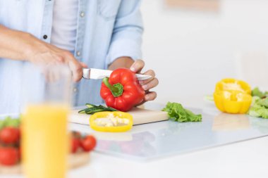 Adam evde salata için kırmızı biber kesiyor. Sağlıklı yemek..
