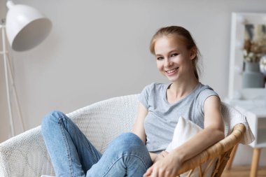 Huzurlu, rahat bir genç kadın oturma odasında rahat bir sandalyede hayal kuruyor, stres yok. Evde dinlenmenin tadını çıkarıyorum.. 