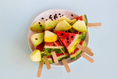 Taze, olgun karpuz ve karpuz dilimlenmiş beyaz tabakta karpuz çekirdekleri, tahta çubuklar, üst manzara