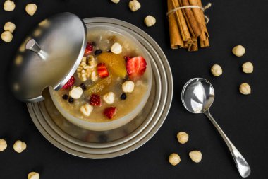 Tarçın çubukları, fındık ve kaşıkla geleneksel Türk Tatlısı veya Nuh 'un Gemisi Pudingi.