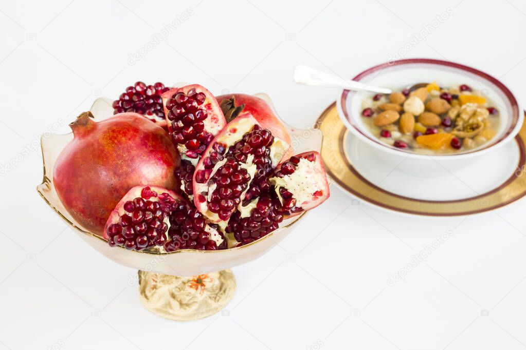 Fresh pomegranate fruits on white surface with ashure bowl.Selective focus of horizontal view