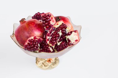 Olgun, taze nar meyveleri beyaz yüzeyde cam kasede dilimlenmiş fotokopi alanı ile.