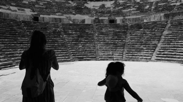 在土耳其安塔利亚市阿斯彭多斯 一位身着侧影的母亲和她的女儿的身后正在观看一场古老的戏剧 — 图库照片