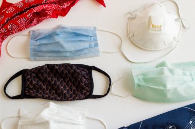 Beyaz arka planda çeşitli tıbbi ve yıkanabilir kumaş maskeler, üst görünüm