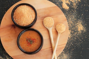 Geleneksel Türk Ev Yapımı Kuru Çorba, Tarhana taneleri ve ahşap kaşıklarla ahşap tepside güveç kasesinde pişirilmiş.