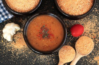 Geleneksel Türk Ev Yapımı Kuru Çorba, Tarhana taneleri ve siyah yüzeyde güveç kasesinde malzemelerle pişirilmiş.