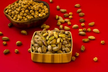 Taze, çıtır şam fıstığı ve kırmızı arka planda ahşap kaselerde sarı nohut. 