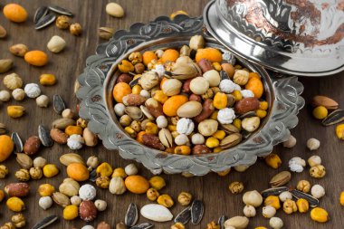 Manzaranın üstünde, ahşap bir masada, eski bir bakır tabakta kuru fındıklar.