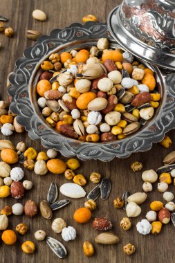 Manzaranın üstünde, ahşap bir masada, eski bir bakır tabakta kuru fındıklar.