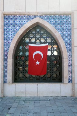 Seljuk döneminden kalma mavi kiremitlerle süslenmiş kemerli pencere ve asılı duran bir Türk Bayrağı 