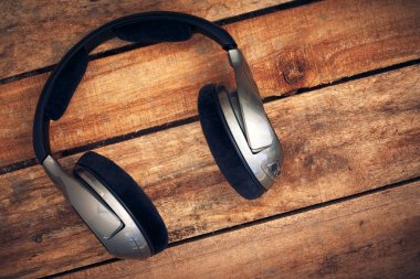 Kablosuz kulaklık bir rustik ahşap masanın üzerinde yatan bir dizi üst bir görünümünü resepsiyon. Görüntüye eklenen stil ve tahıl etkisi.