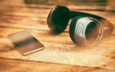 Kablosuz kulaklık ve cep telefonu dışında rustik ahşap bir masa yatan bir dizi 45 derecelik bakış. Görüntüye eklenen stil ve tahıl etkisi.