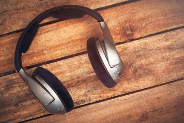 Kablosuz kulaklık bir rustik ahşap masanın üzerinde yatan bir dizi üst bir görünümünü resepsiyon. Görüntüye eklenen stil ve tahıl etkisi.