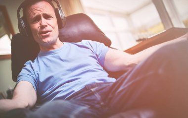Rahatlatıcı bir koltuk kablosuz kulaklık müzik dinleme keyfi bir adam. Görüntüye eklenen stil ve tahıl etkisi.