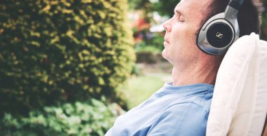 Rahatlatıcı bir koltuk kablosuz kulaklık müzik dinleme keyfi bir adam. Görüntüye eklenen stil ve tahıl etkisi.