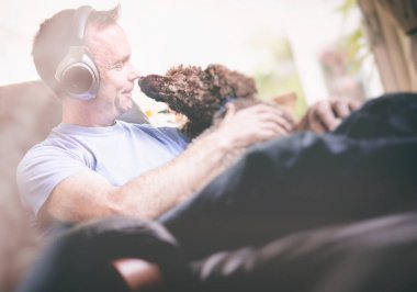 Rahatlatıcı bir koltuk kablosuz kulaklık müzik dinleme keyfi bir adam. Görüntüye eklenen stil ve tahıl etkisi.