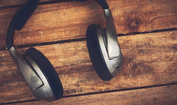 Kablosuz kulaklık bir rustik ahşap masanın üzerinde yatan bir dizi üst bir görünümünü resepsiyon. Görüntüye eklenen stil ve tahıl etkisi.