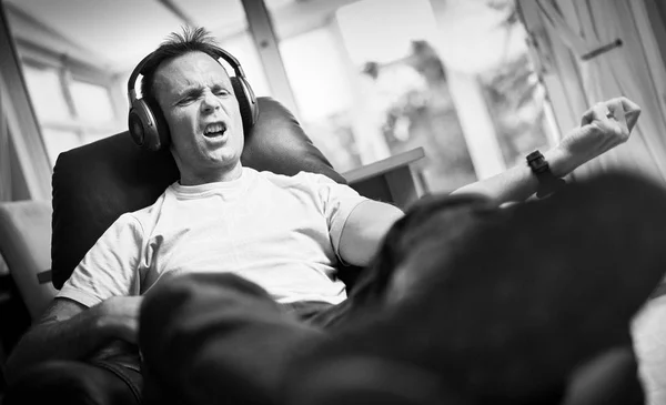 リラックスできる肘掛け椅子で無線ヘッドフォンで音楽を聴くことを楽しむ男 イメージに追加するスタイリングと粒度の効果 — ストック写真