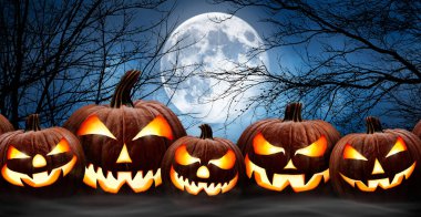 Arka arkaya beş tane ürkütücü Cadılar Bayramı balkabağı, Jack O Lantern, şeytani yüzüyle ve gözleri tahtadan bir bankta, sisli bir gece ormanı ve dolunay arkaplanı olan bir masa.