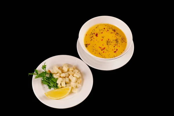Kırmızı biberli mercimek kremalı çorba, karabiber ve kraker. Siyah arkaplan