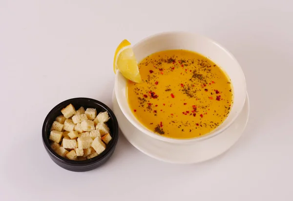 Kırmızı biberli mercimek kremalı çorba, karabiber ve kraker. Beyaz arkaplan