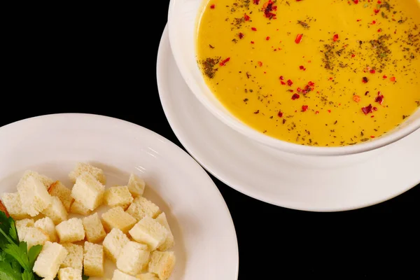 Kırmızı biberli mercimek kremalı çorba, karabiber ve kraker. Siyah arkaplan