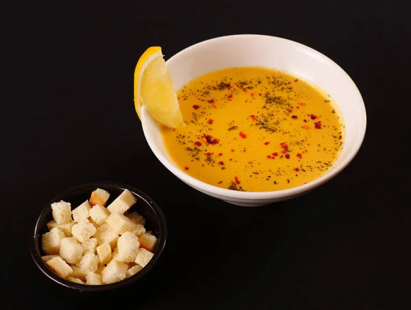 Kırmızı biberli mercimek kremalı çorba, karabiber ve kraker. Siyah arkaplan
