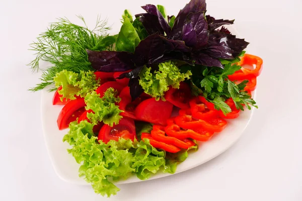 Légumes tranchés, feuilles de laitue, basilic, aneth sur un plat. Fond blanc — Photo