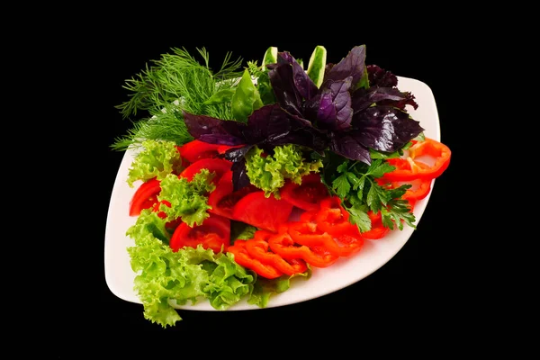 Sliced vegetables, leaves of lettuce, Basil, dill on a dish. Black background