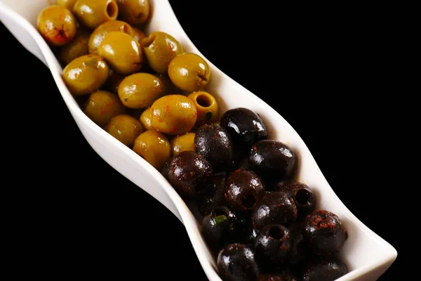 Оливки - зеленые и черные на длинном блюде. Чёрный фон — стоковое фото