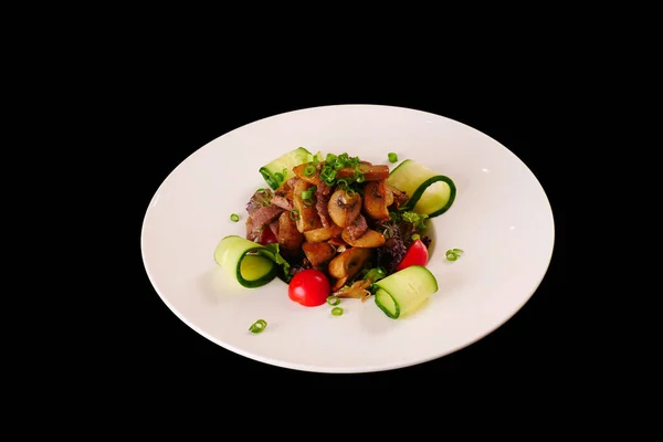 Kızarmış et ve yeşil soğanlı mantar salatası ve salatalık ve domates.