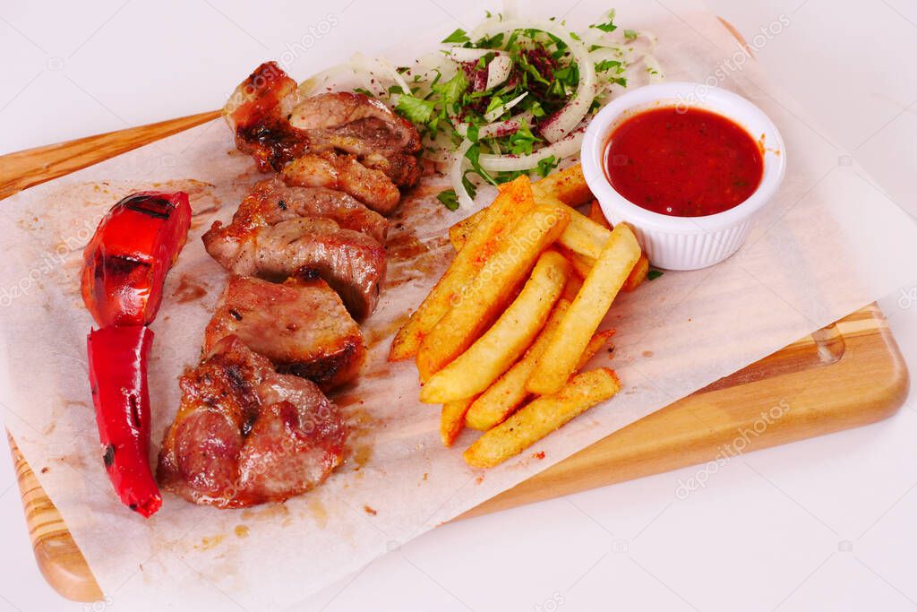 Grilled lamb chops, pepper, tomato, French fries, ketchup onion on wooden Board
