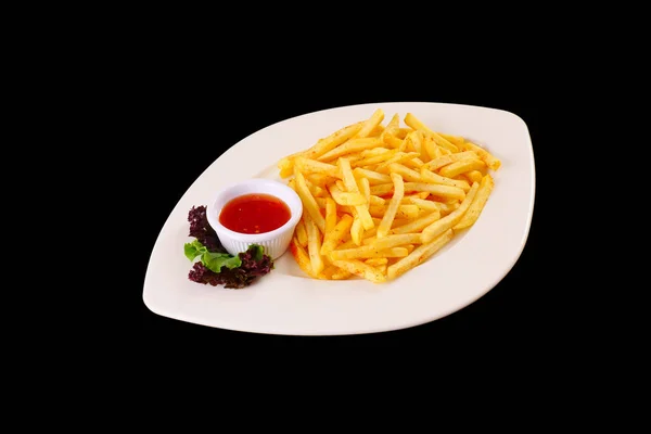 Papas fritas con salsa de tomate y lechuga en un plato blanco. Fondo negro Imagen De Stock