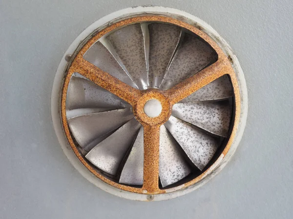 Ancient rusted air fan in a window glass