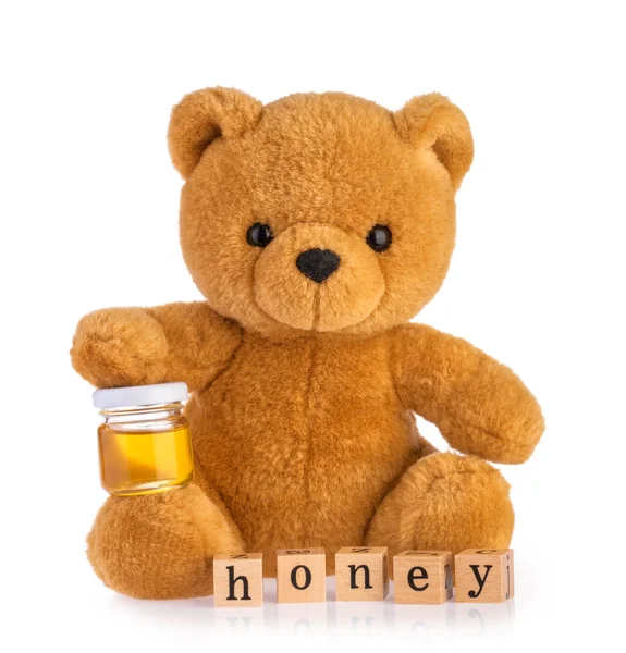 Osito de peluche sosteniendo miel olla aislado fondo blanco — Foto de Stock