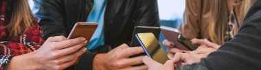 Bir grup insan ellerinde akıllı telefonlar, teknolojiye kafayı takmış gençler ve barda cep telefonlarını birbiri ile takılıyor.