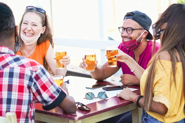 Multiracial friends cheering with beer and smiling laughing with each other - Coronavirus/face mask concept