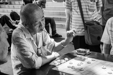 Yaşlı Çinli adam Xiangqi oynuyor, veya Çin satrancı SIngapur 'daki Buda Dişi Relic Tapınağı' nın dışında. Siyah ve beyaz. Yakın plan.