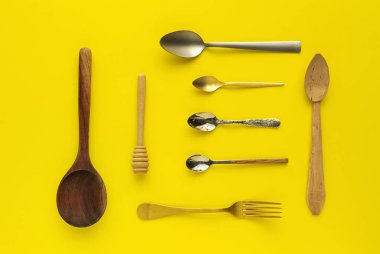 Sarı arka planda kaşıklar ve çatallar