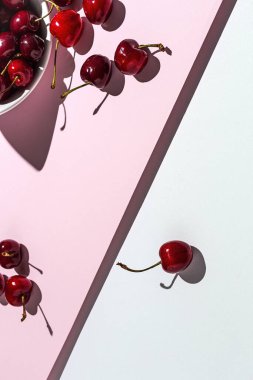 Renkli arka planlarda güçlü güneş ışığı olan taze mevsimlik kırmızı kirazlar.