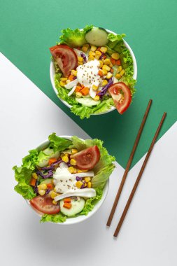 Domatesli ev yapımı taze marul salatası, kırmızı soğan, mısır, havuç, salatalık ve yukarıdan gelen renklerde susam sosu. Sağlıklı yiyecekler. Vejetaryen yemeği.. 