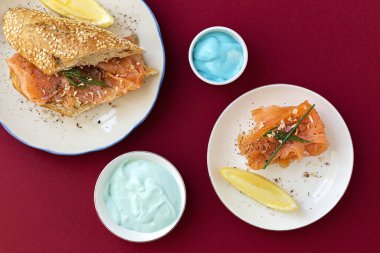 Norveç usulü tütsülenmiş somon kanapeleri, limon, mavi peynir sosu, biber ve tuz, yukarıdan, renkli arka planlar. Düz yatıyordu. Üst görünüm
