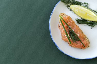 Norveç usulü tütsülenmiş somon kanapeleri, limon, mavi peynir sosu, biber ve tuz, yukarıdan, renkli arka planlar. Düz yatıyordu. Üst görünüm