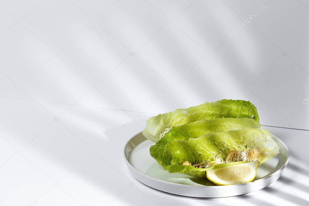 Homemade Caesar salad with chicken, lettuce, lemon, toast, caesar sauce, cheese and garlic.On white background.Healthy food concept
