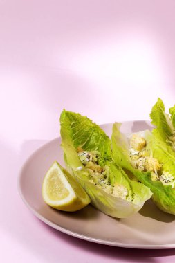 Tavuk, marul, limon, tost, sezar sosu, peynir ve sarımsaklı ev yapımı Sezar salatası. Pembe arka planda. Sağlıklı gıda kavramı.