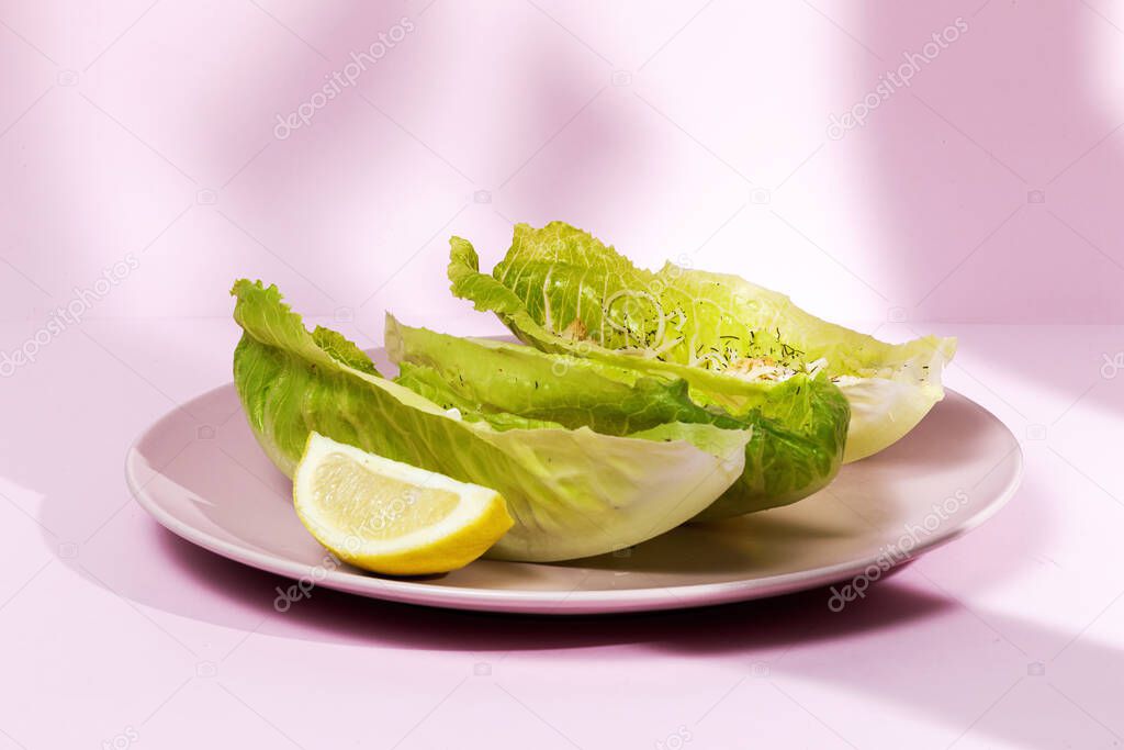 Homemade Caesar salad with chicken, lettuce, lemon, toast, caesar sauce, cheese and garlic.On pink background.Healthy food concept